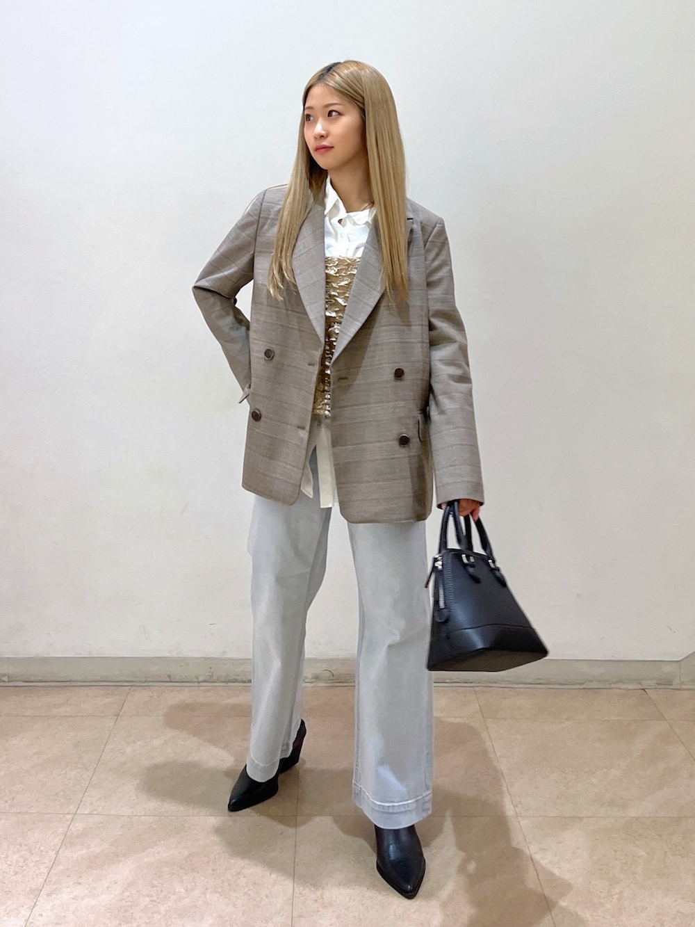 ブラック系のショルダーバッグ、ブルー系のデニムパンツ、ブラック系のパンプスを着用したレディースの春コーディネートの2枚目の写真