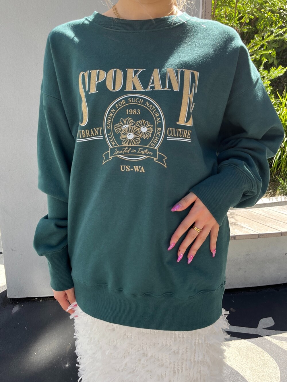 グリーン系のTシャツ/カットソー、ホワイト系のスカート、ブラック系のブーツを着用したレディースの秋コーディネートの7枚目の写真