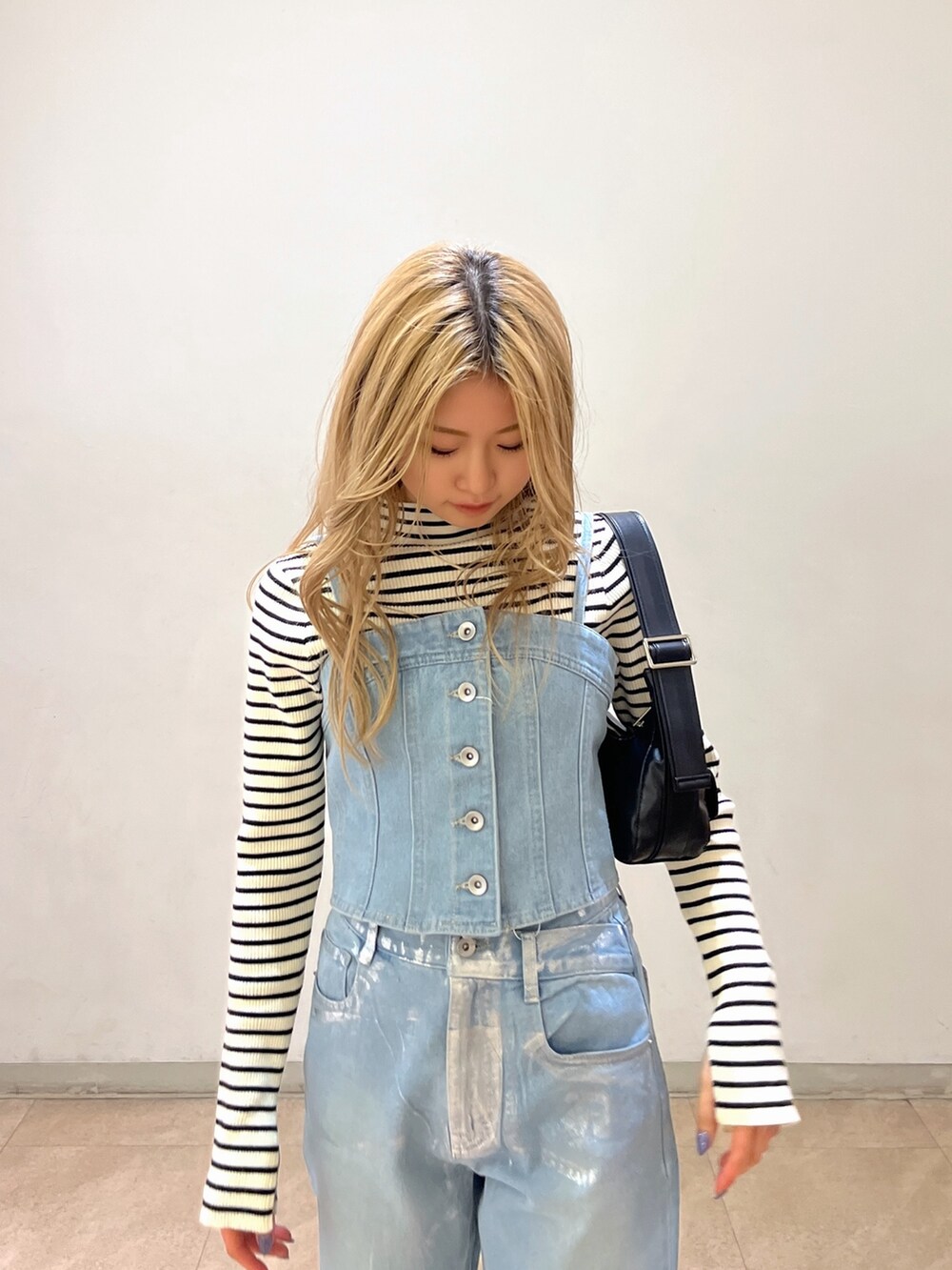 ブルー系のベスト、ホワイト系のニット/セーター、ブラック系のショルダーバッグを着用したレディースの冬コーディネートの6枚目の写真