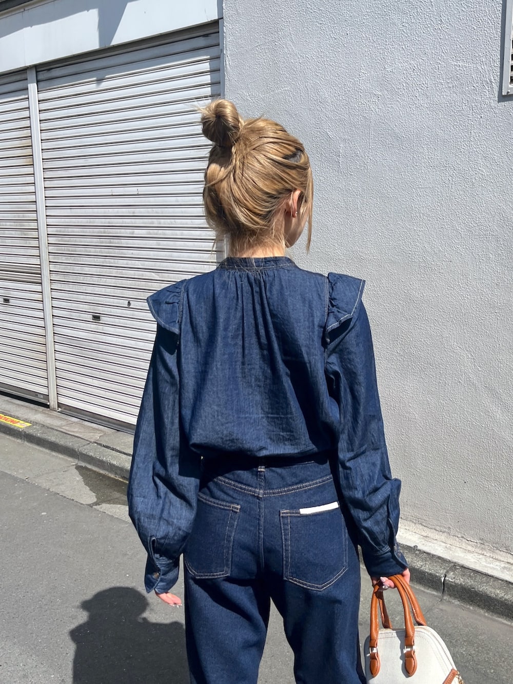 ブルー系のシャツ/ブラウス、ブルー系のデニムパンツ、ブラウン系のショルダーバッグを着用したレディースの春コーディネートの5枚目の写真