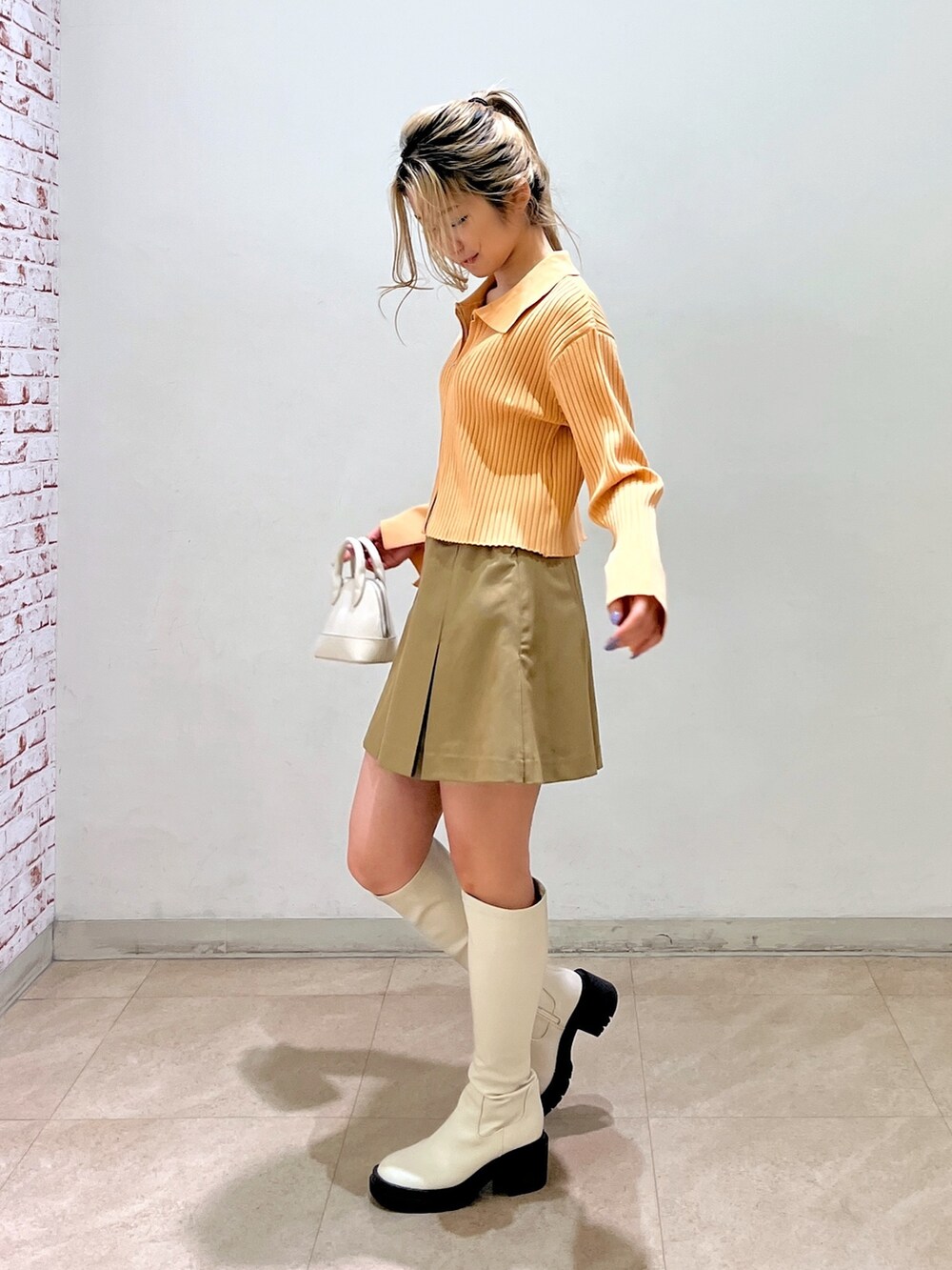 ベージュ系のニット/セーター、ホワイト系のショルダーバッグ、ベージュ系のスカートを着用したレディースの冬コーディネートの4枚目の写真