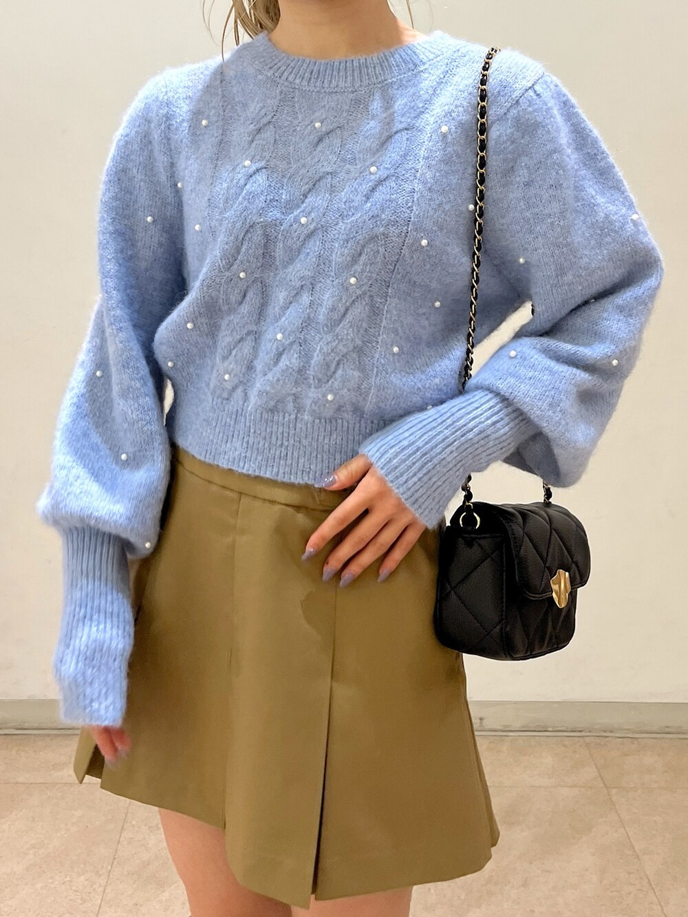 ブルー系のニット/セーター、ブラック系のショルダーバッグ、ベージュ系のスカートを着用したレディースの冬コーディネートの10枚目の写真