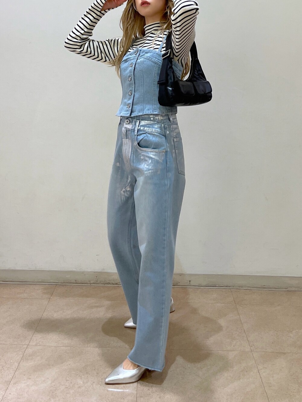 ブルー系のベスト、ホワイト系のニット/セーター、ブラック系のショルダーバッグを着用したレディースの冬コーディネートの2枚目の写真