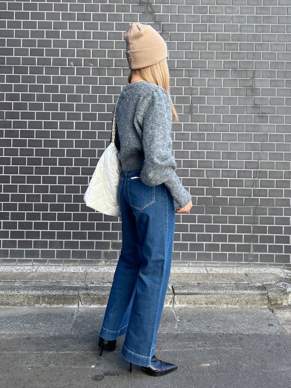 ブルー系のデニムパンツ、グレー系のニット/セーター、ホワイト系のトートバッグを着用したレディースの冬コーディネートの4枚目の写真