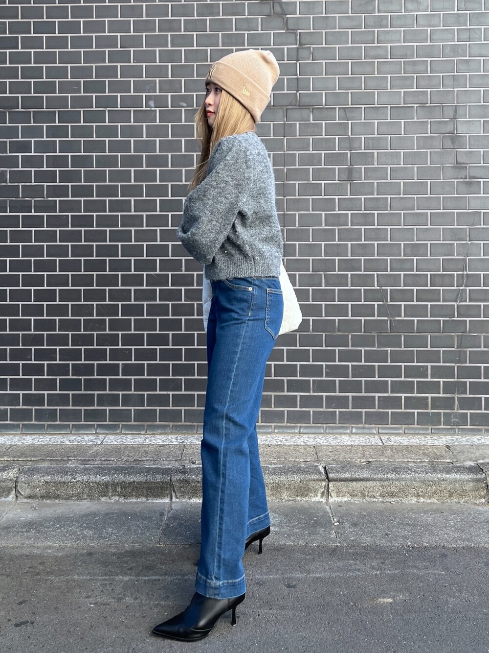 ブルー系のデニムパンツ、グレー系のニット/セーター、ホワイト系のトートバッグを着用したレディースの冬コーディネートの2枚目の写真