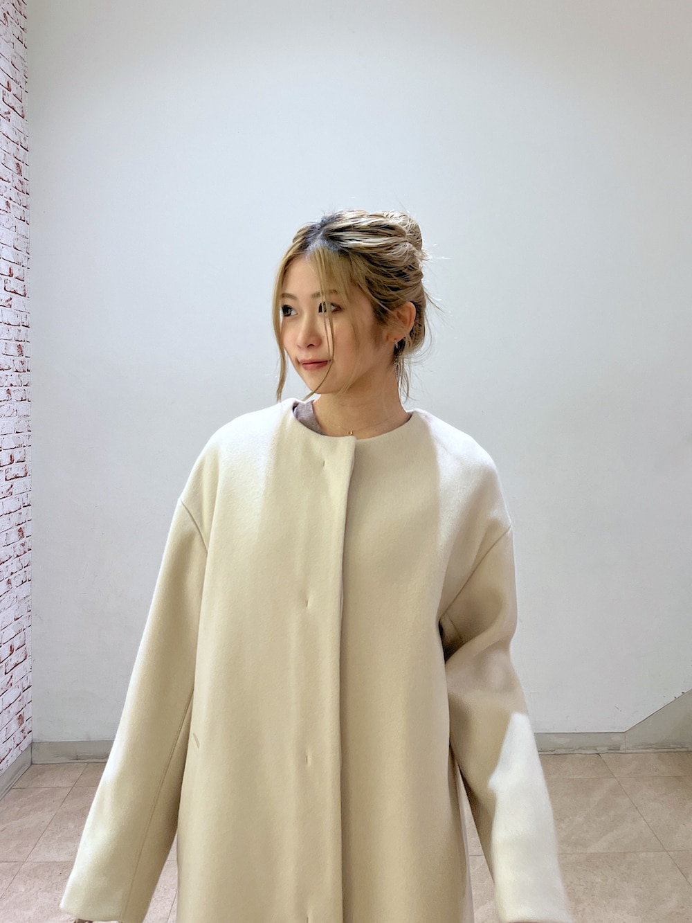 ベージュ系のノーカラーコート、ホワイト系のシャツ/ブラウス、ベージュ系のワンピースを着用したレディースの冬コーディネートの10枚目の写真