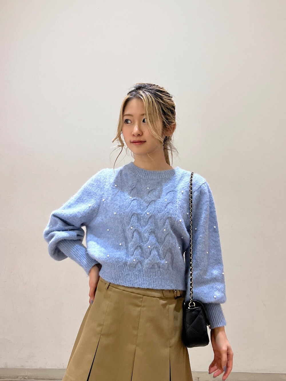 ブルー系のニット/セーター、ブラック系のショルダーバッグ、ベージュ系のスカートを着用したレディースの冬コーディネートの6枚目の写真