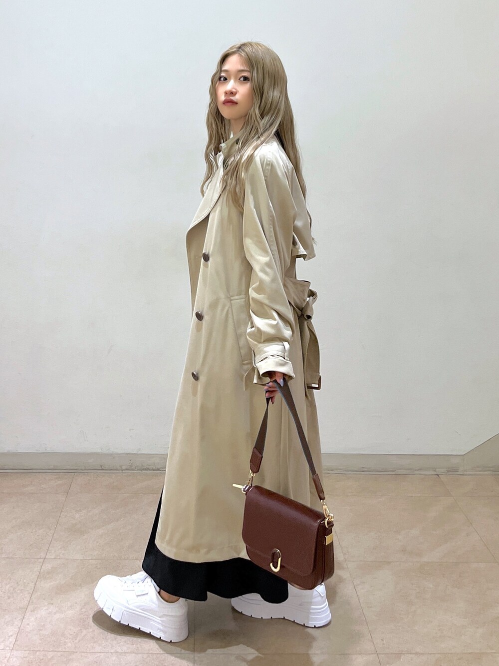 ホワイト系のシャツ/ブラウス、ベージュ系のトレンチコート、ブラウン系のショルダーバッグを着用したレディースの春コーディネートの3枚目の写真
