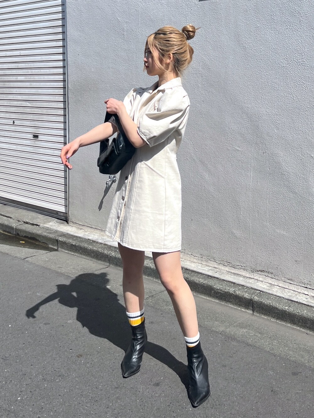 ブラック系のショルダーバッグ、ホワイト系のワンピースを着用したレディースの春コーディネートの2枚目の写真