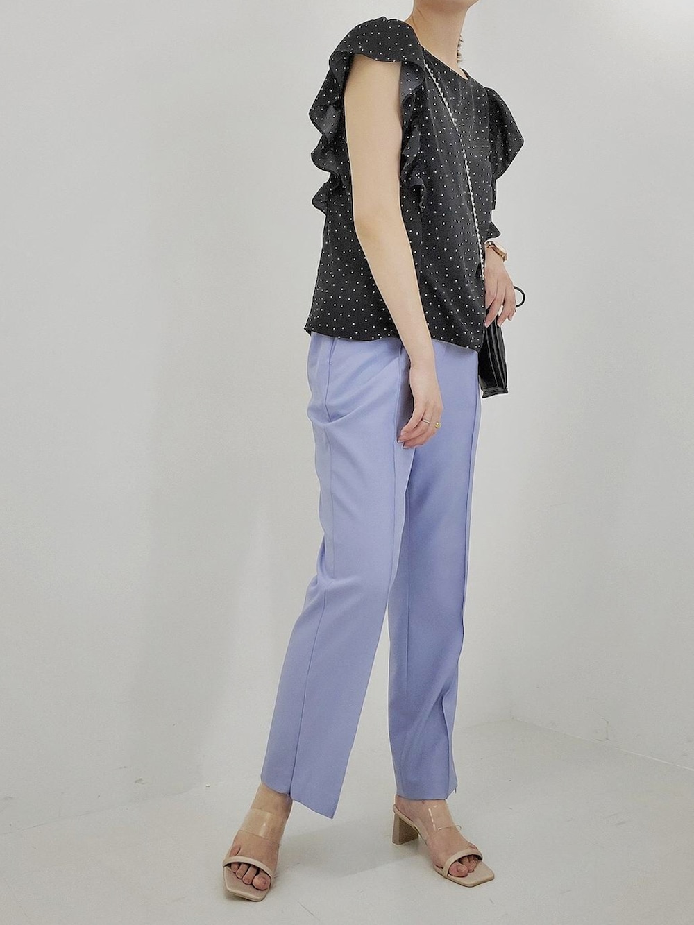 ブラック系のシャツ/ブラウス、ブルー系のスラックス、ベージュ系のサンダルを着用したレディースの夏コーディネートの2枚目の写真