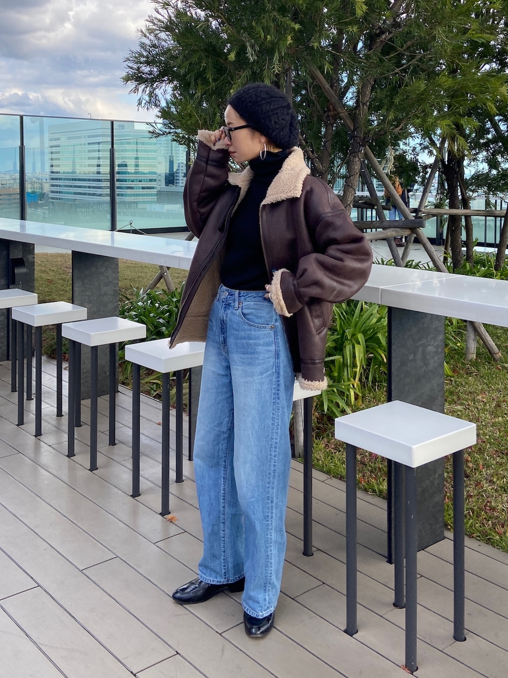 ブルー系のデニムパンツ、ブラック系のニット/セーター、ブラウン系のムートンコートを着用したレディースの冬コーディネートの2枚目の写真