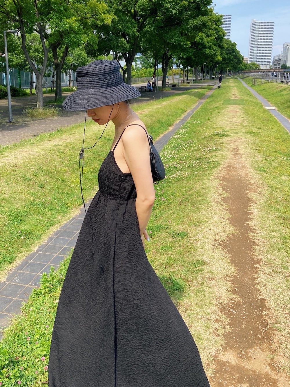 ブラック系のワンピース、ブラック系のサンダル、ブラック系のハットを着用したレディースの春コーディネートの5枚目の写真
