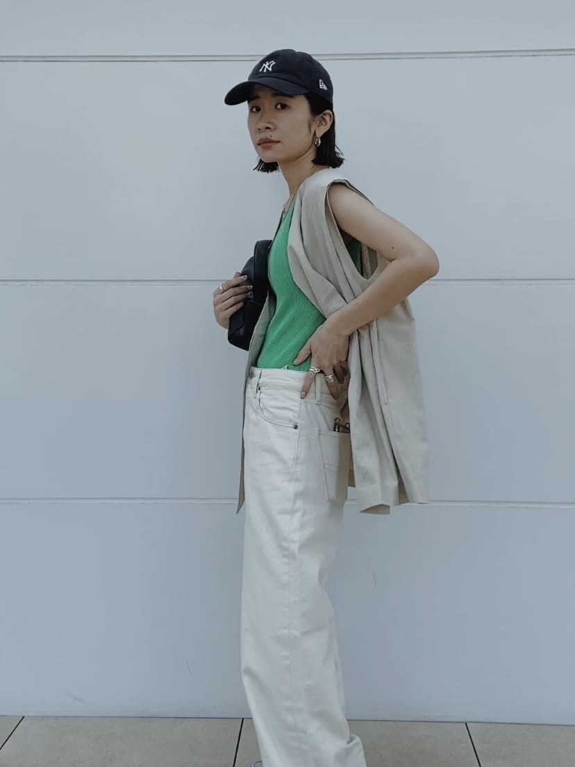 グリーン系のタンクトップ、ホワイト系のベスト、ホワイト系のデニムパンツを着用したレディースの春コーディネートの2枚目の写真