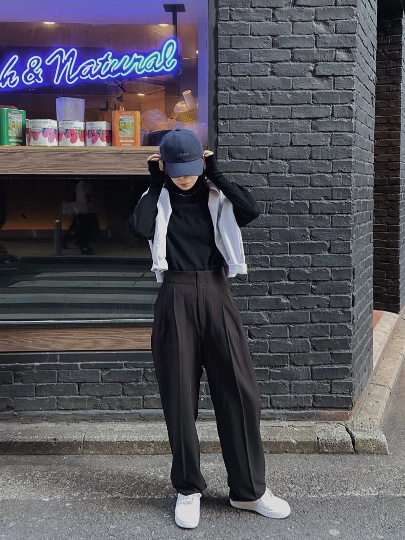 ブラック系のスラックス、グレー系のスウェット、ブルー系のキャップを着用したレディースの冬コーディネートの2枚目の写真