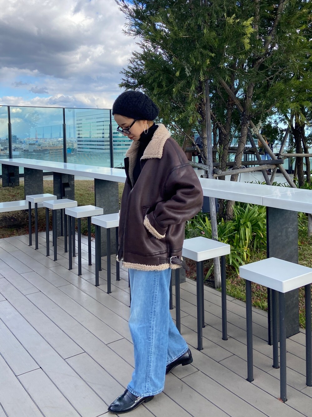 ブルー系のデニムパンツ、ブラック系のニット/セーター、ブラウン系のムートンコートを着用したレディースの冬コーディネートの4枚目の写真