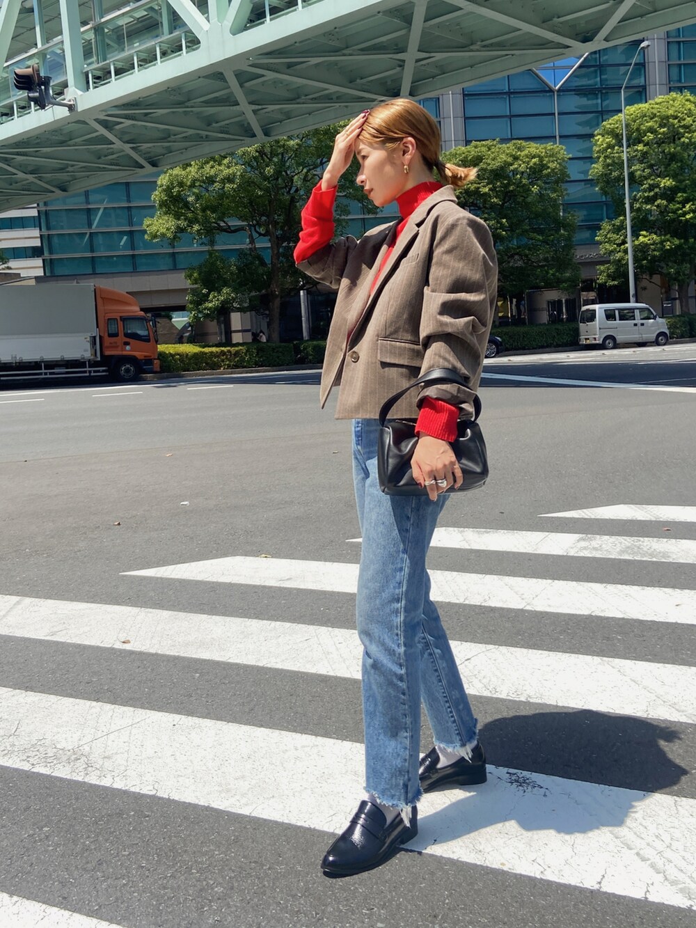レッド系のニット/セーター、ブラウン系のテーラードジャケット、ブルー系のデニムパンツを着用したレディースの夏コーディネートの2枚目の写真