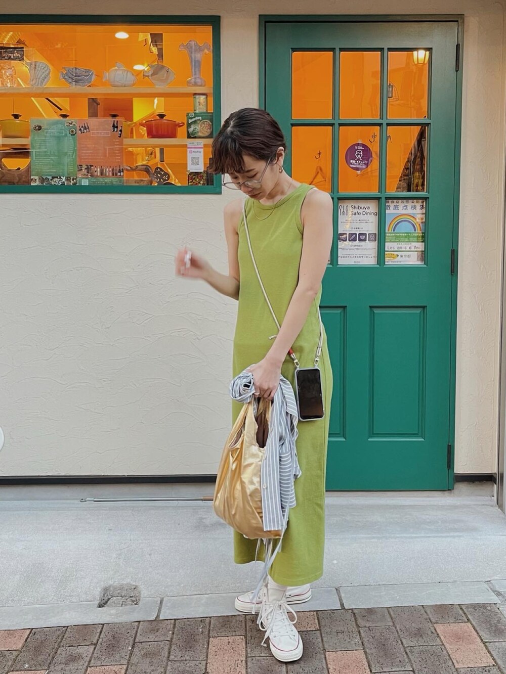 グリーン系のワンピース、ゴールド系のエコバッグ/サブバッグ、ブルー系のシャツ/ブラウスを着用したレディースの春コーディネートの3枚目の写真