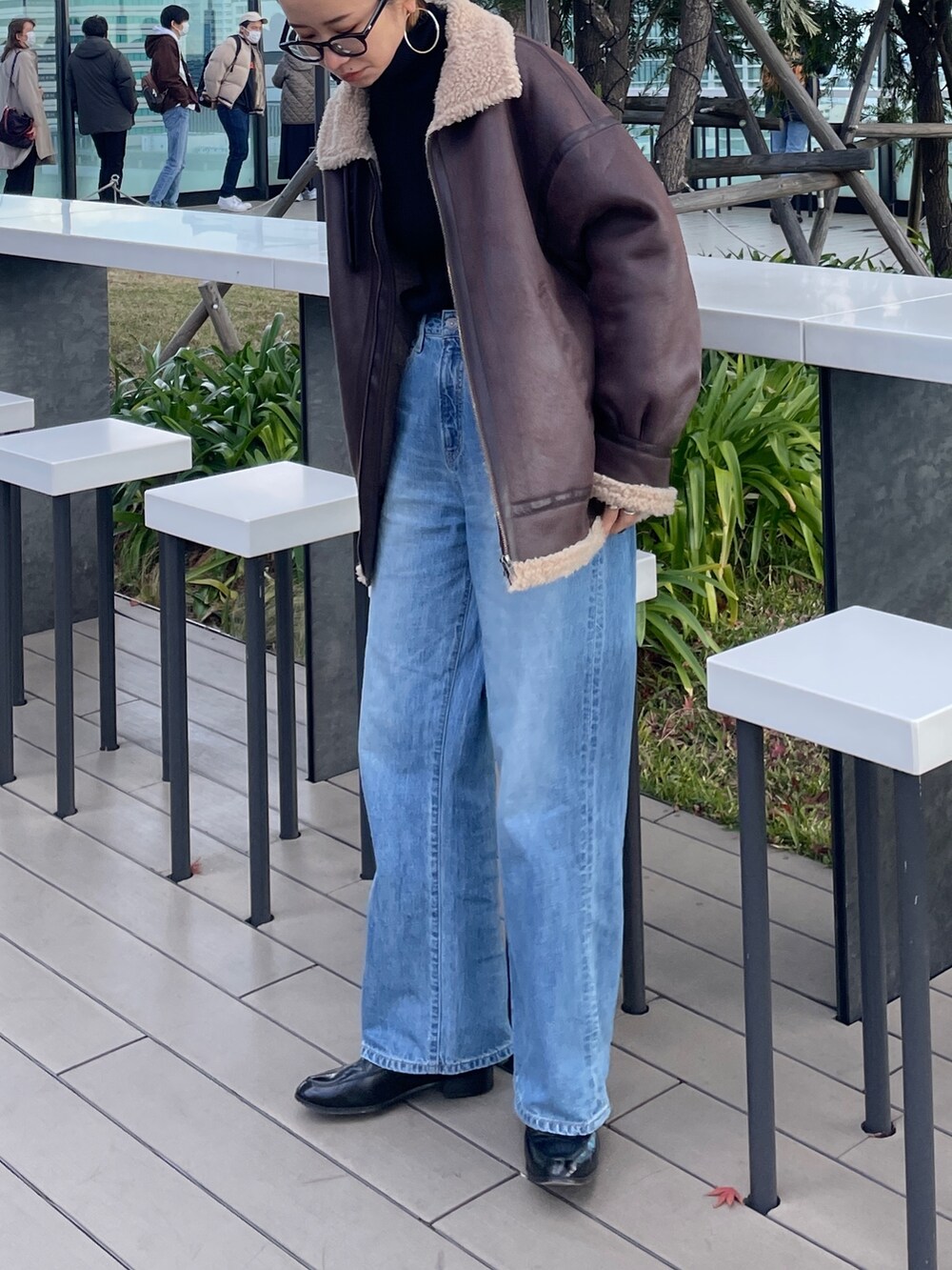 ブルー系のデニムパンツ、ブラック系のニット/セーター、ブラウン系のムートンコートを着用したレディースの冬コーディネートの5枚目の写真