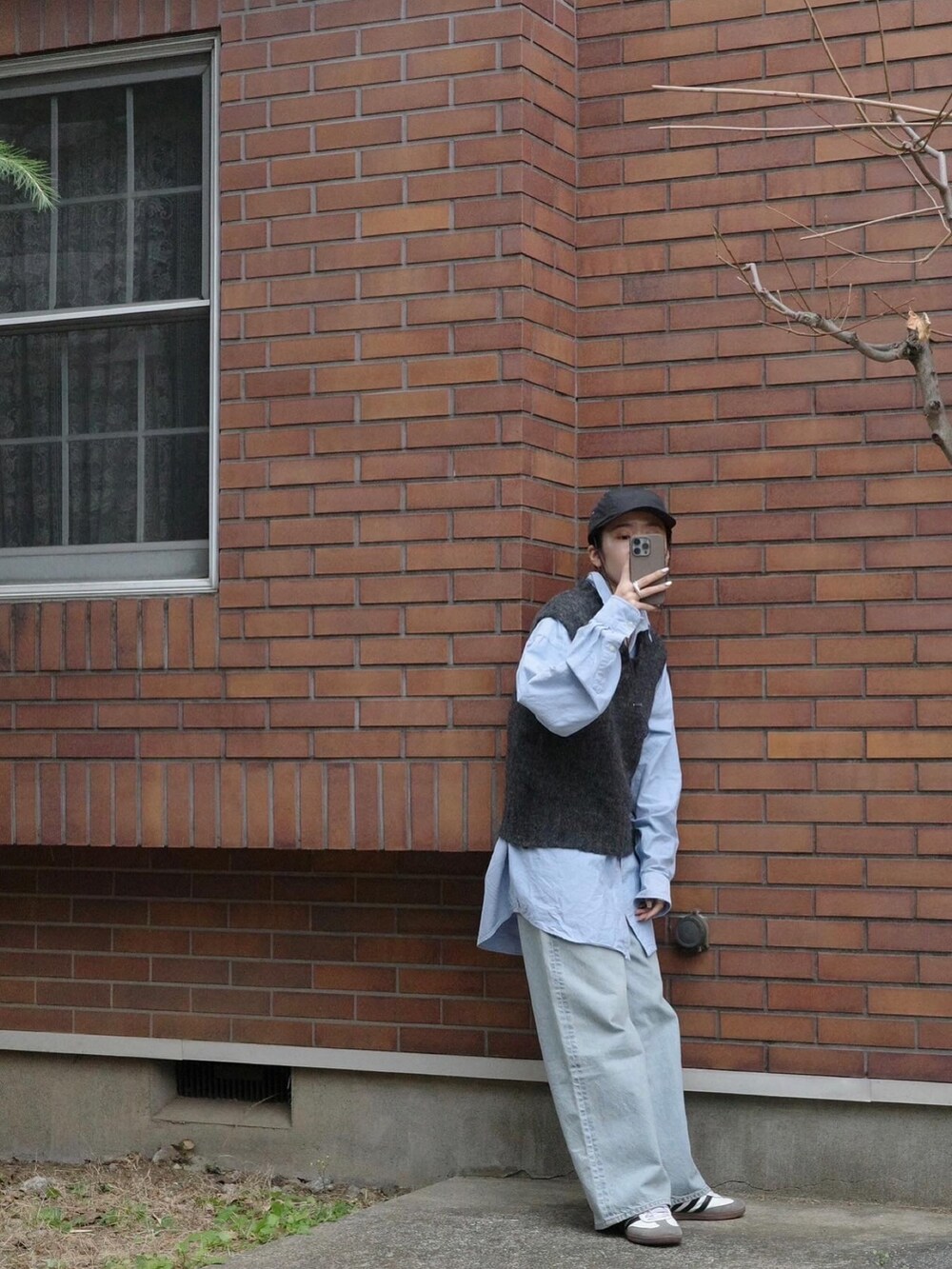 ブルー系のデニムパンツ、ホワイト系のシューズ、グレー系のベストを着用したレディースの冬コーディネートの5枚目の写真