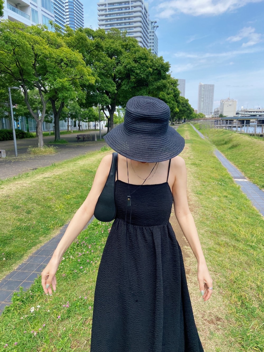 ブラック系のワンピース、ブラック系のサンダル、ブラック系のハットを着用したレディースの春コーディネートの4枚目の写真