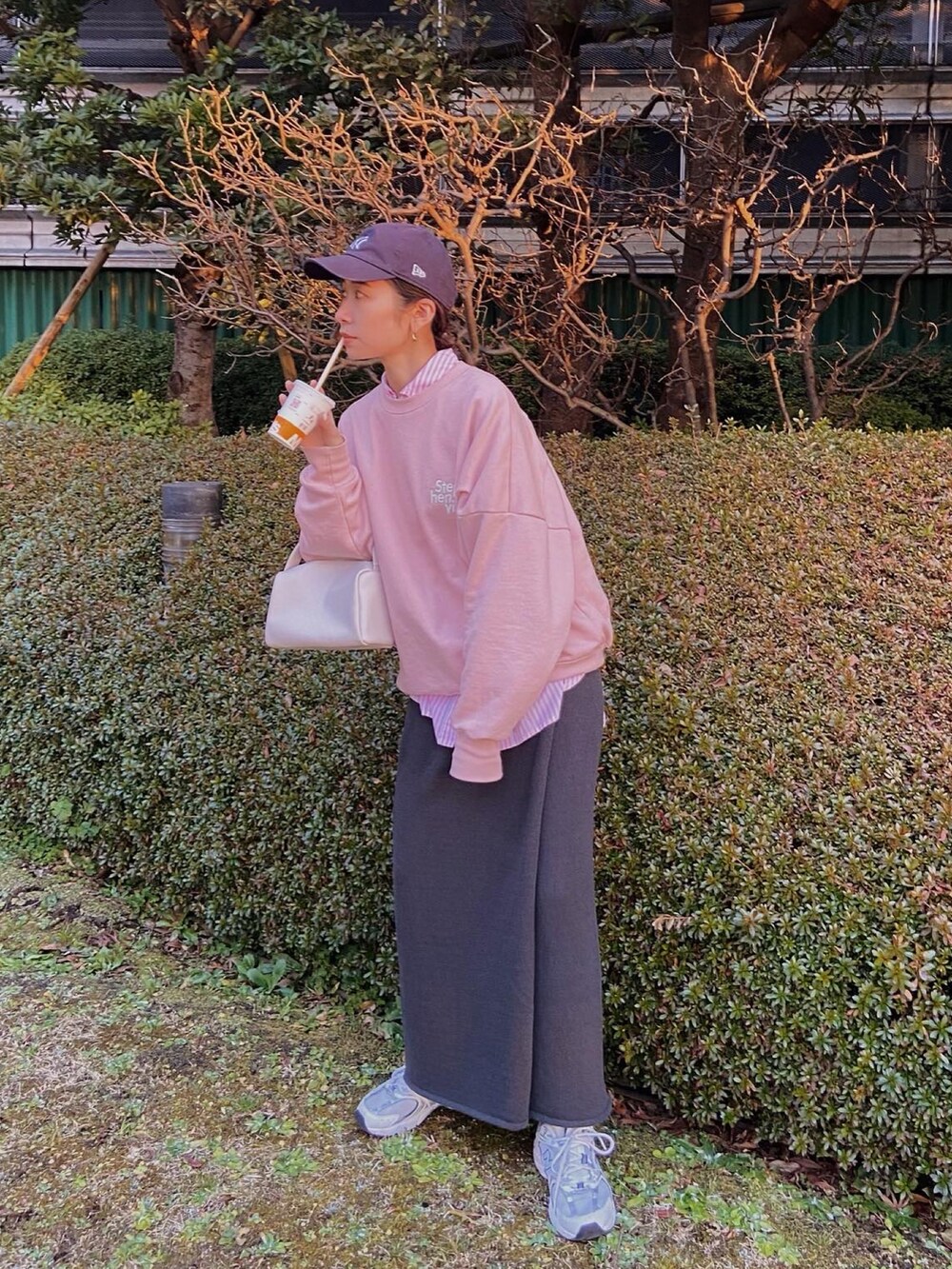 ピンク系のスウェット、ピンク系のハンドバッグ、グレー系のスカートを着用したレディースの冬コーディネートの2枚目の写真