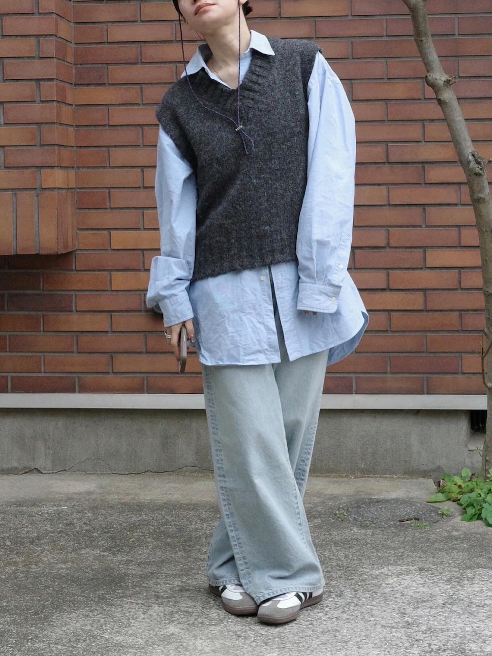 ブルー系のデニムパンツ、ホワイト系のシューズ、グレー系のベストを着用したレディースの冬コーディネートの2枚目の写真