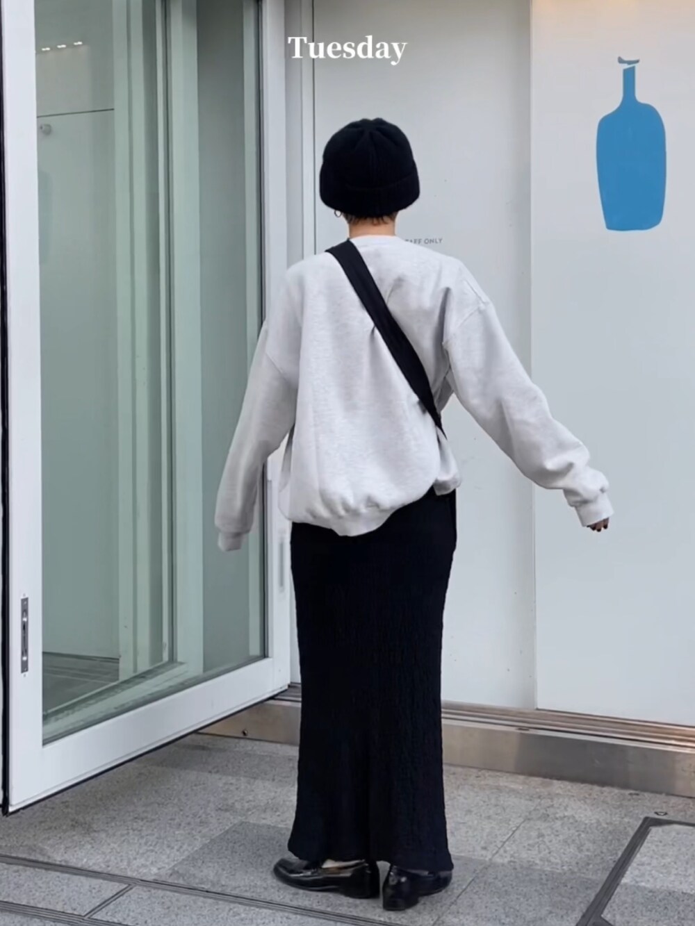 ブラック系のスカート、ブラック系のショルダーバッグ、ブラック系のニットキャップ/ビーニーを着用したレディースの冬コーディネートの2枚目の写真