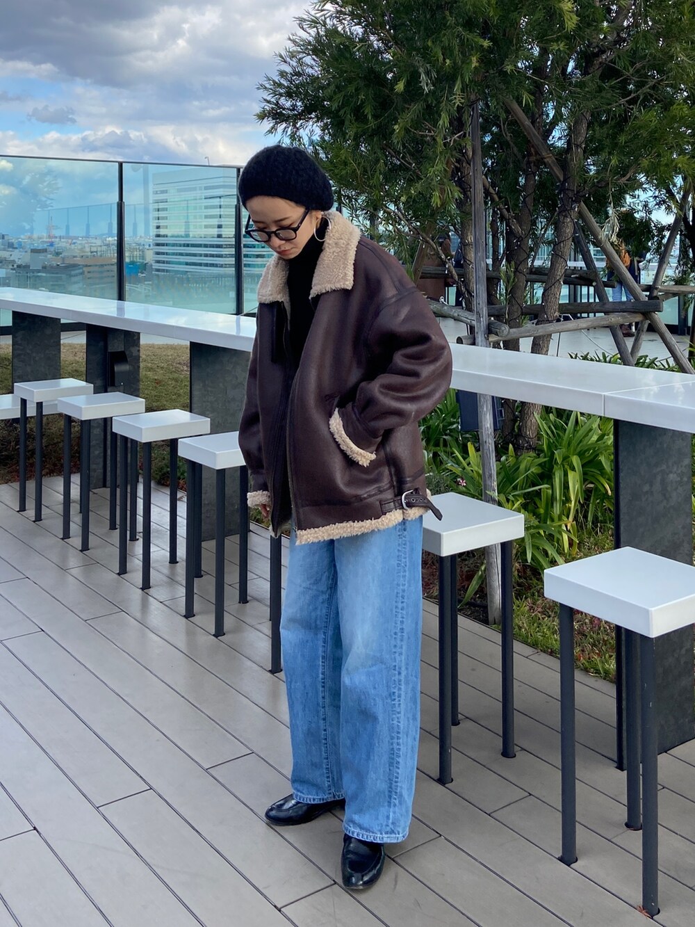 ブルー系のデニムパンツ、ブラック系のニット/セーター、ブラウン系のムートンコートを着用したレディースの冬コーディネートの3枚目の写真