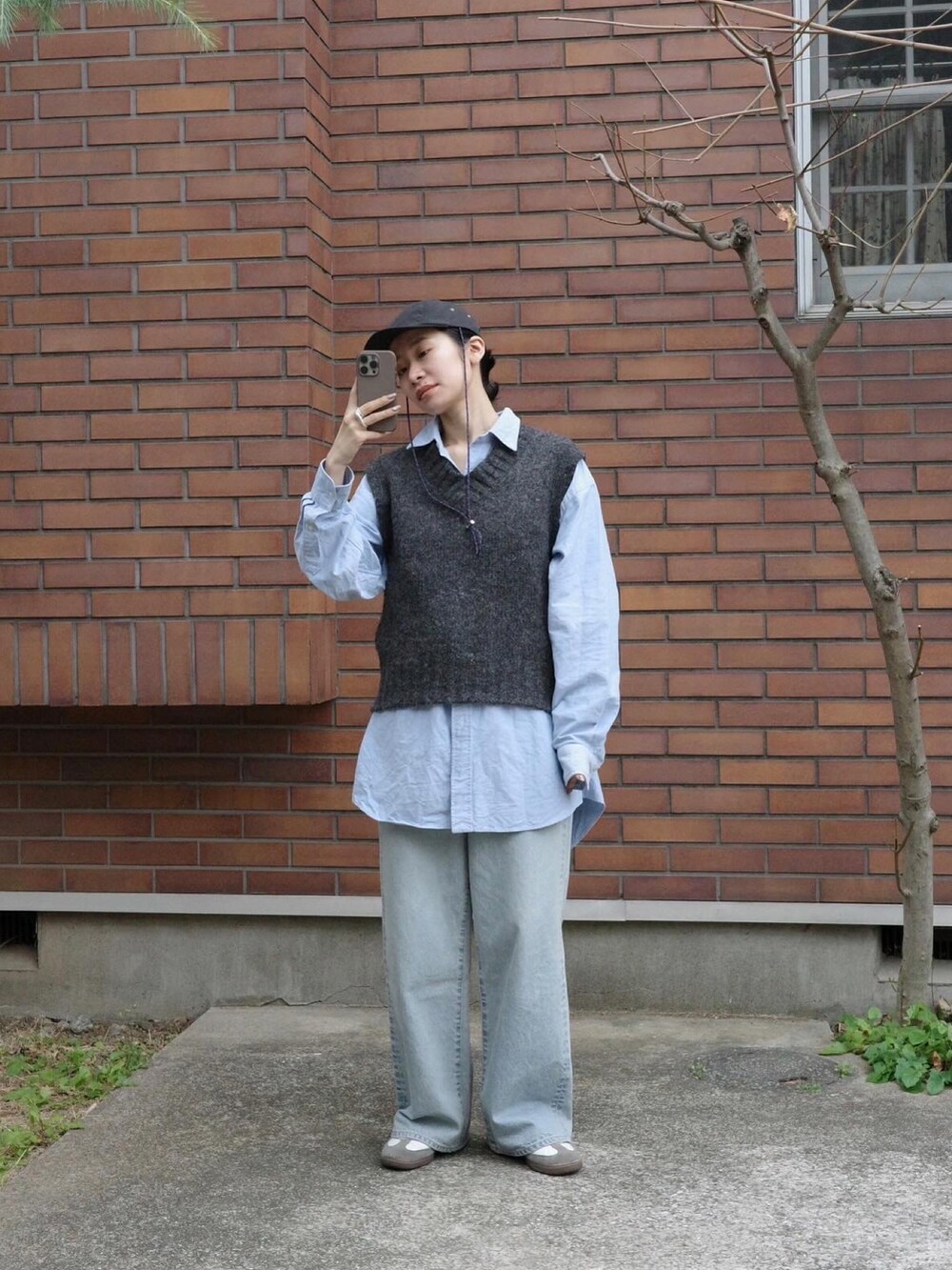 ブルー系のデニムパンツ、ホワイト系のシューズ、グレー系のベストを着用したレディースの冬コーディネートの3枚目の写真