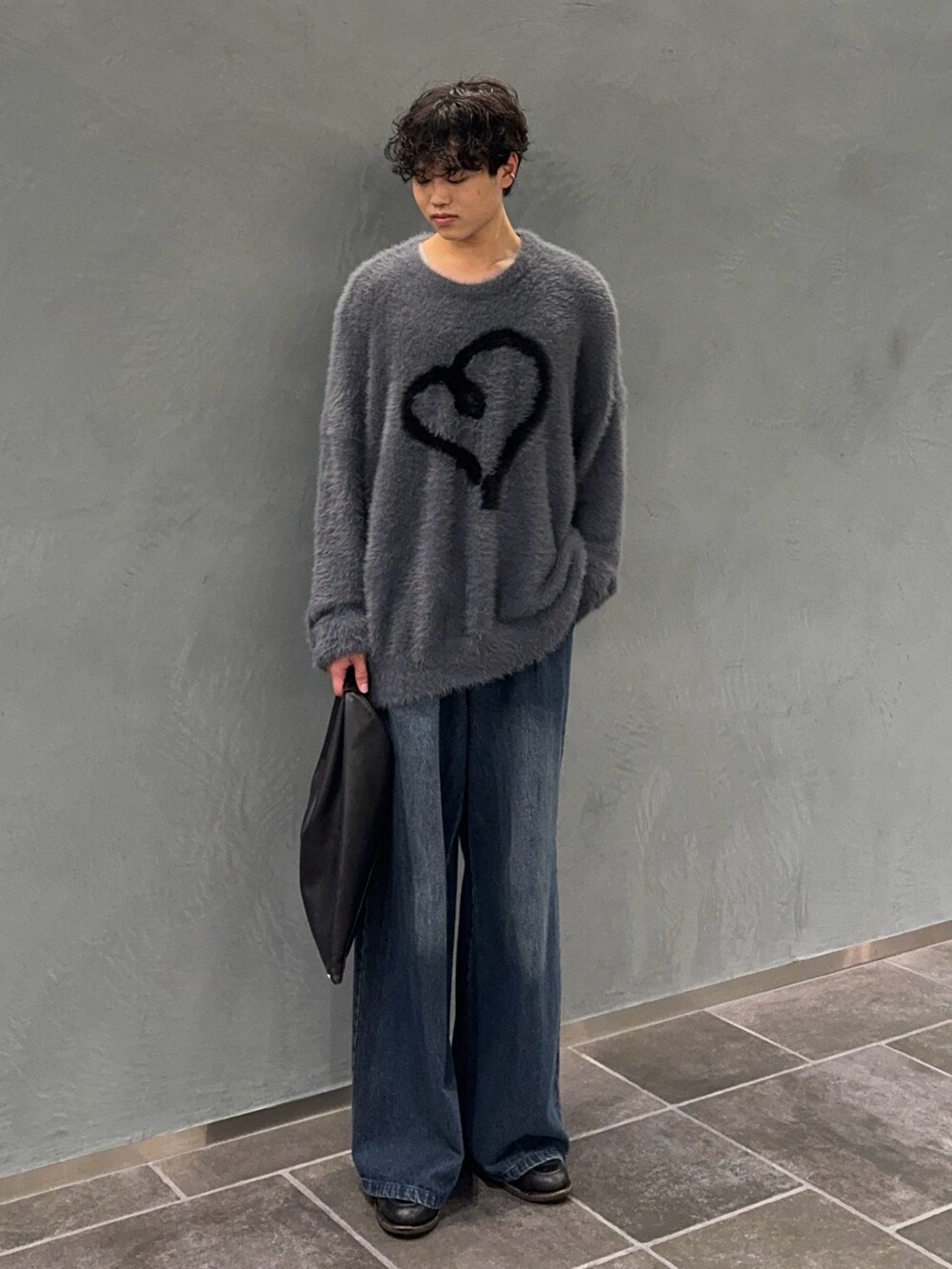 グレー系のニット/セーター、ブラック系のトートバッグ、ブルー系のデニムパンツを着用したメンズの秋コーディネートの2枚目の写真