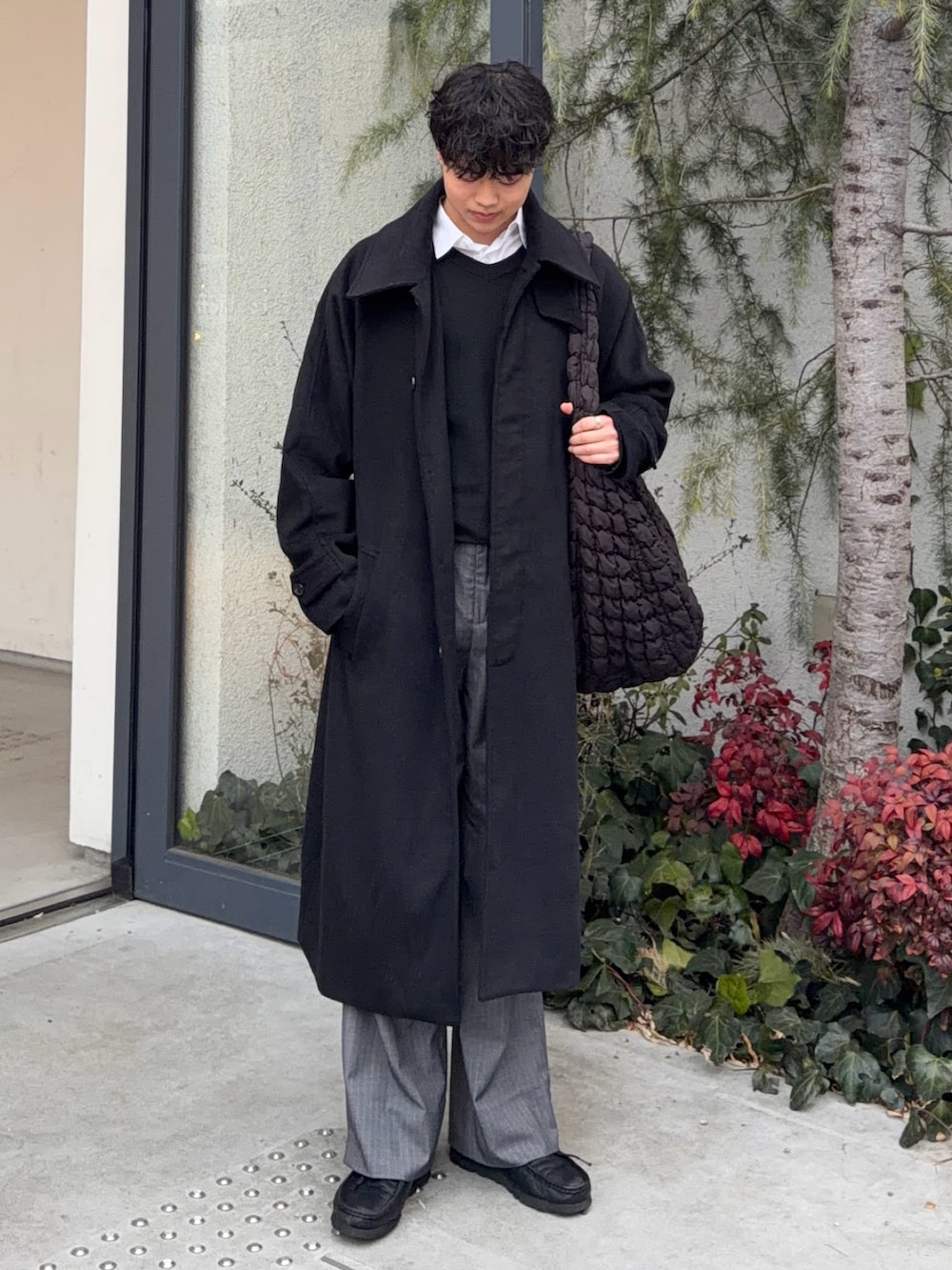 グレー系のスラックス、ブラック系のニット/セーター、ブラック系のステンカラーコートを着用したメンズの冬コーディネートの3枚目の写真