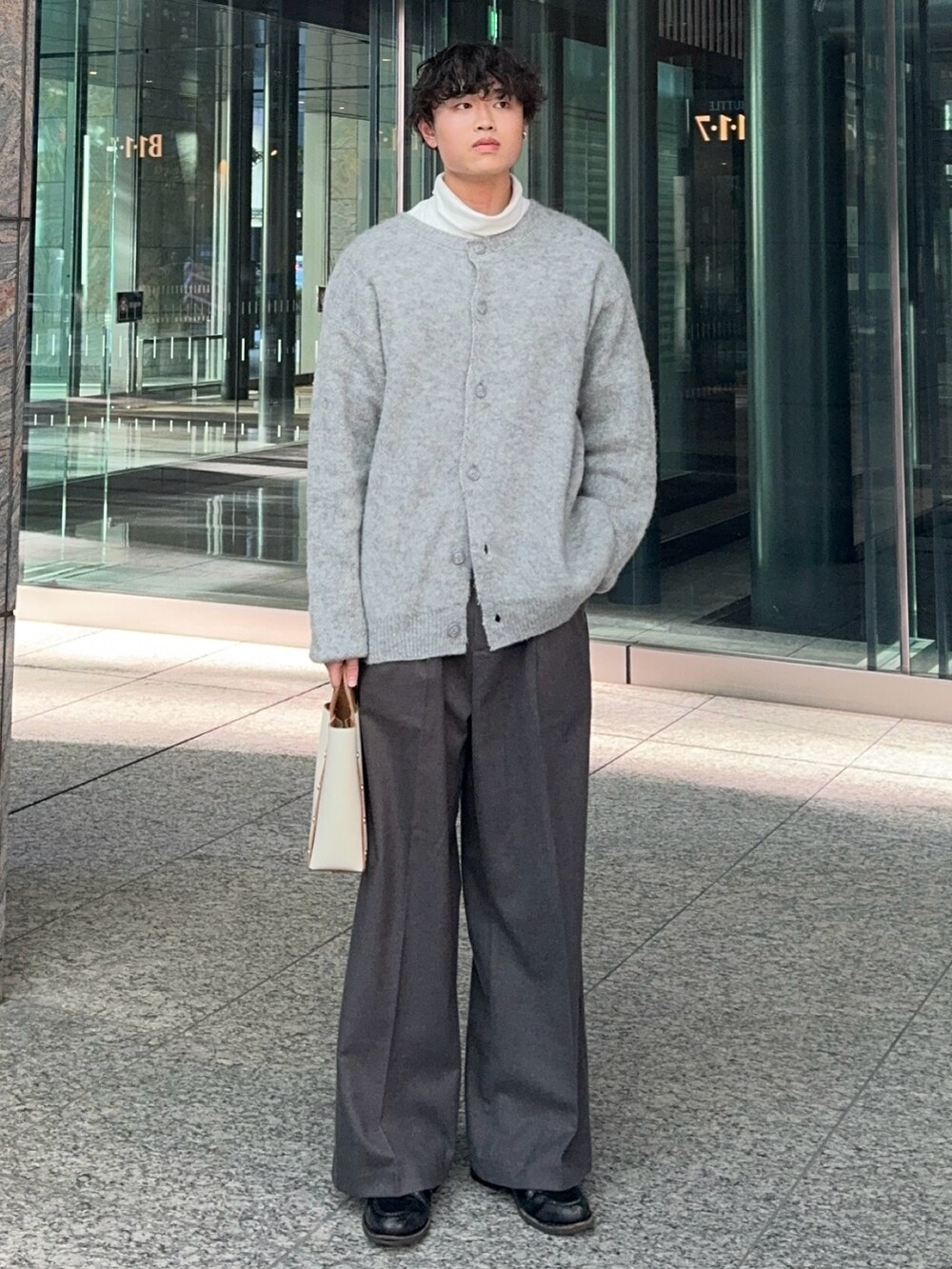 グレー系のカーディガン/ボレロ、ホワイト系のハンドバッグ、ブラック系のローファーを着用したメンズの冬コーディネートの2枚目の写真