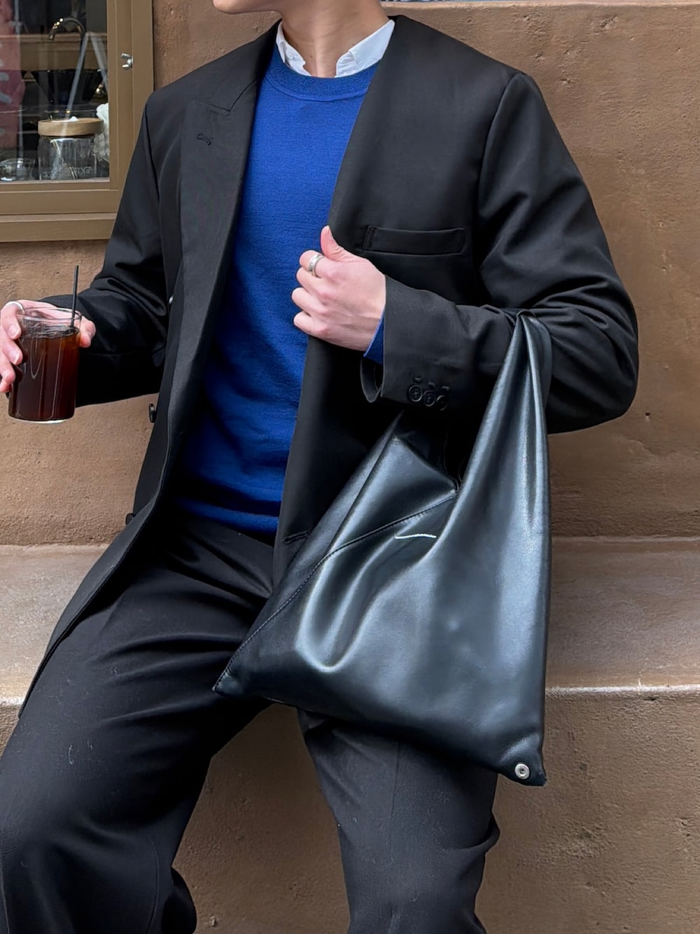 ブラック系のテーラードジャケット、ブルー系のニット/セーター、ブラック系のトートバッグを着用したメンズの春コーディネートの4枚目の写真