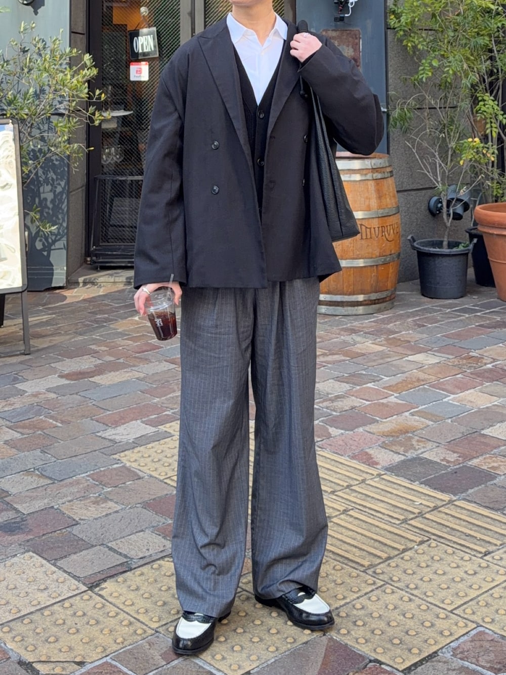 ブラック系のテーラードジャケット、ブラック系のトートバッグ、グレー系のスラックスを着用したメンズの冬コーディネートの2枚目の写真