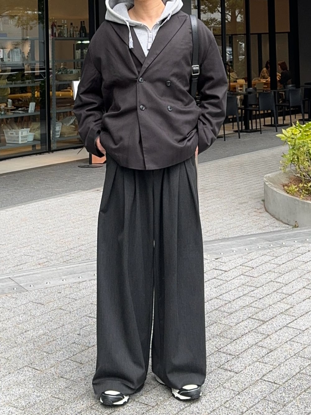 ブラック系のテーラードジャケット、グレー系のパーカー、ブラック系のスラックスを着用したメンズの冬コーディネートの3枚目の写真