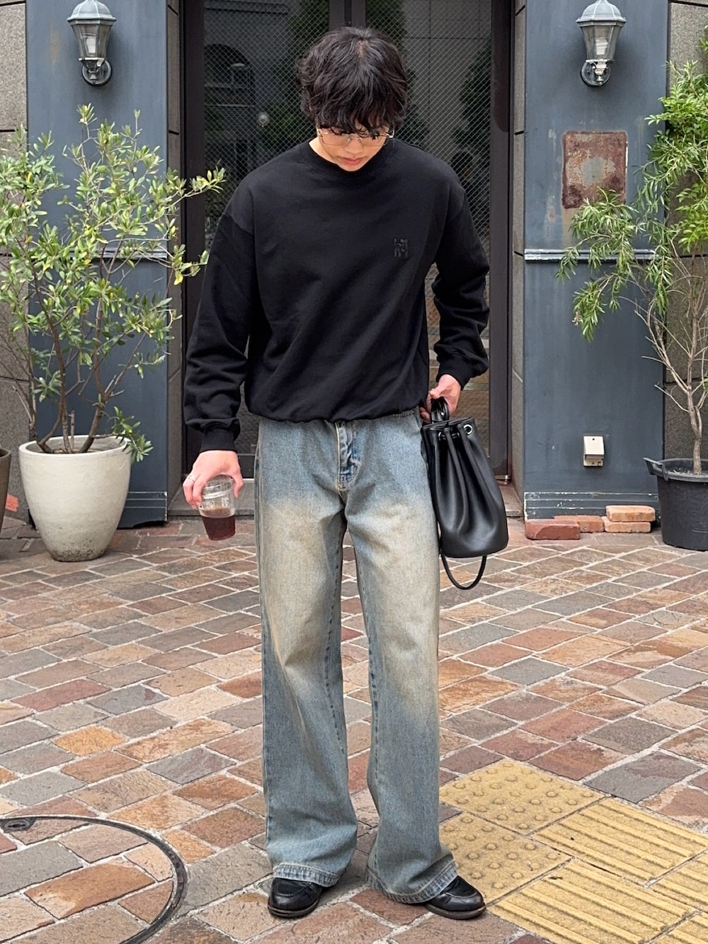 ブラック系のスウェット、ブルー系のデニムパンツ、ブラック系のショルダーバッグを着用したメンズの秋コーディネートの3枚目の写真