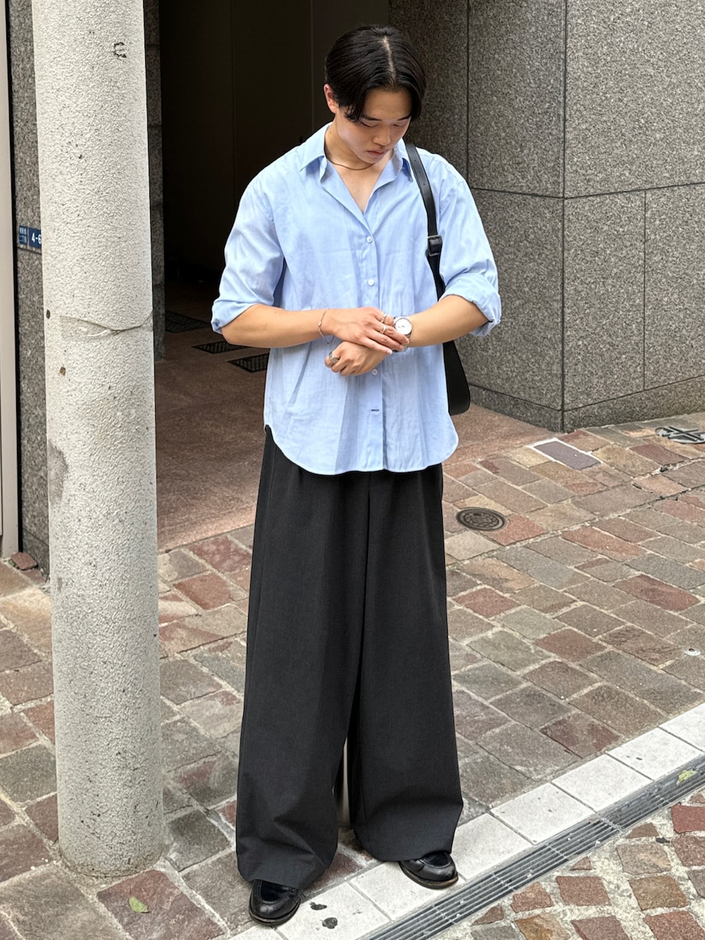 ブラック系のショルダーバッグ、グレー系のスラックス、ブラック系のローファーを着用したメンズの夏コーディネートの4枚目の写真