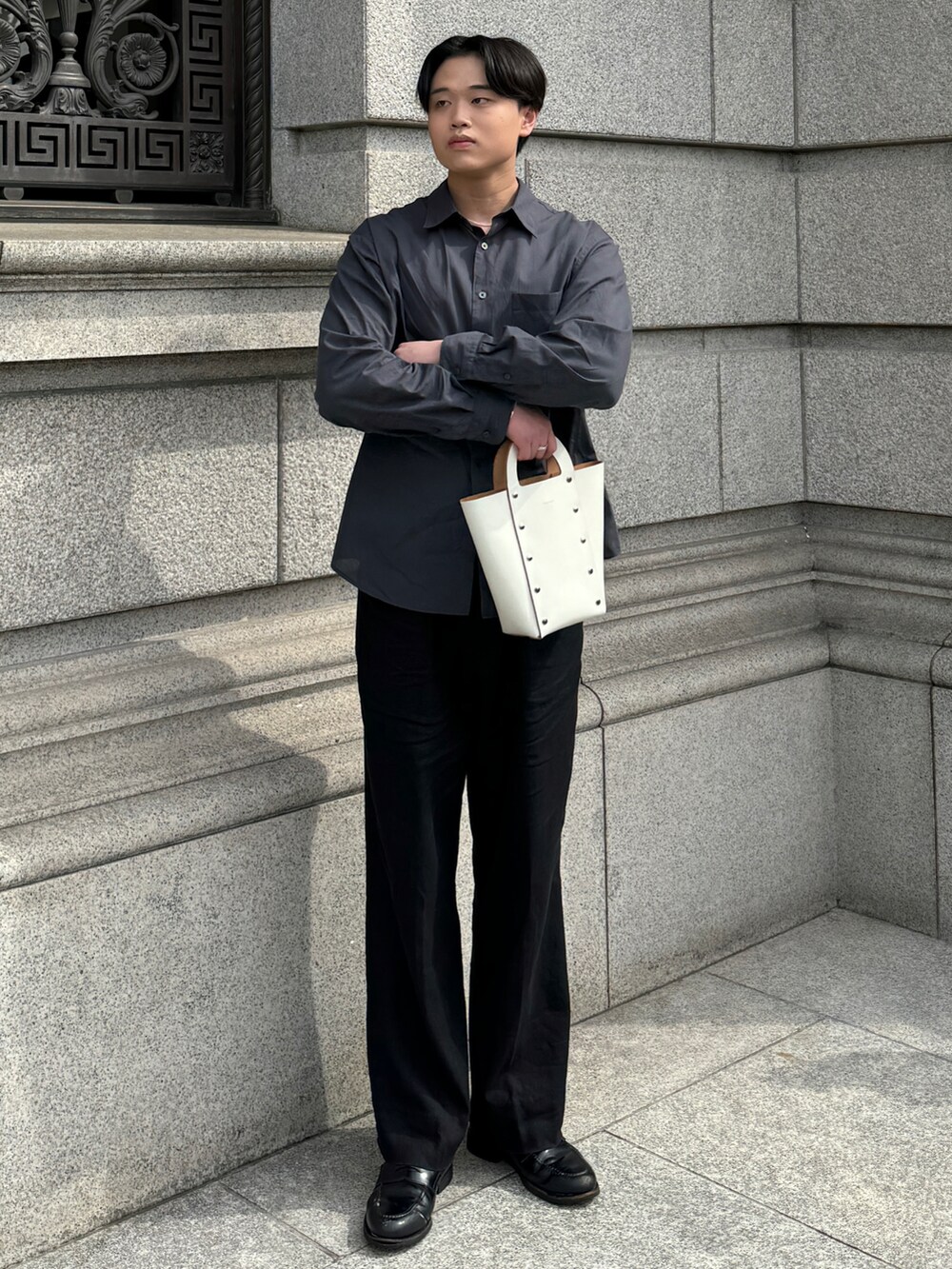 ホワイト系のハンドバッグ、ブラック系のローファー、シルバー系のネックレスを着用したメンズの春コーディネートの2枚目の写真