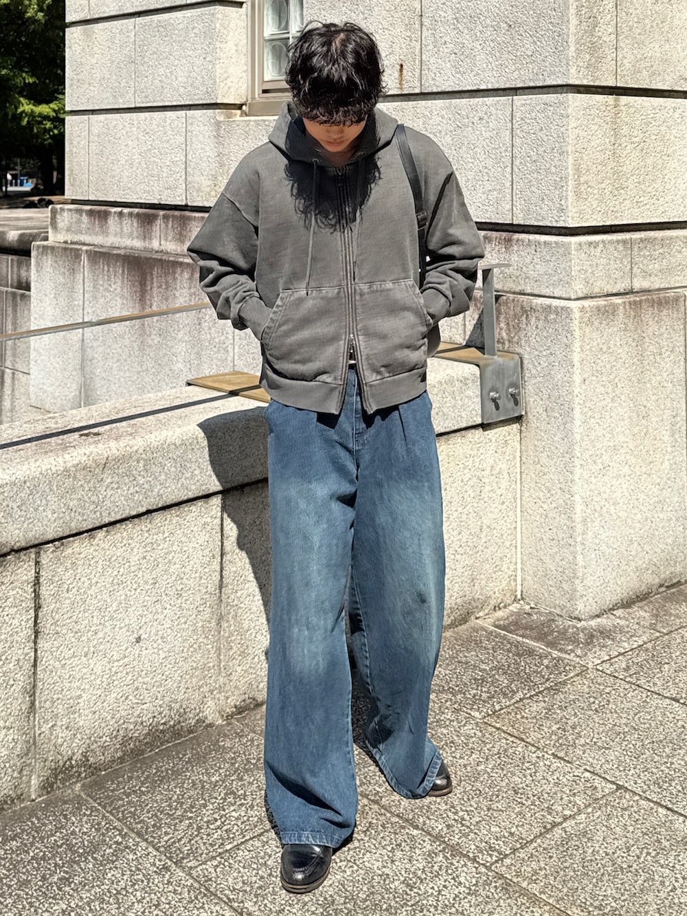 グレー系のパーカー、ブルー系のデニムパンツ、ブラック系のローファーを着用したメンズの秋コーディネートの2枚目の写真