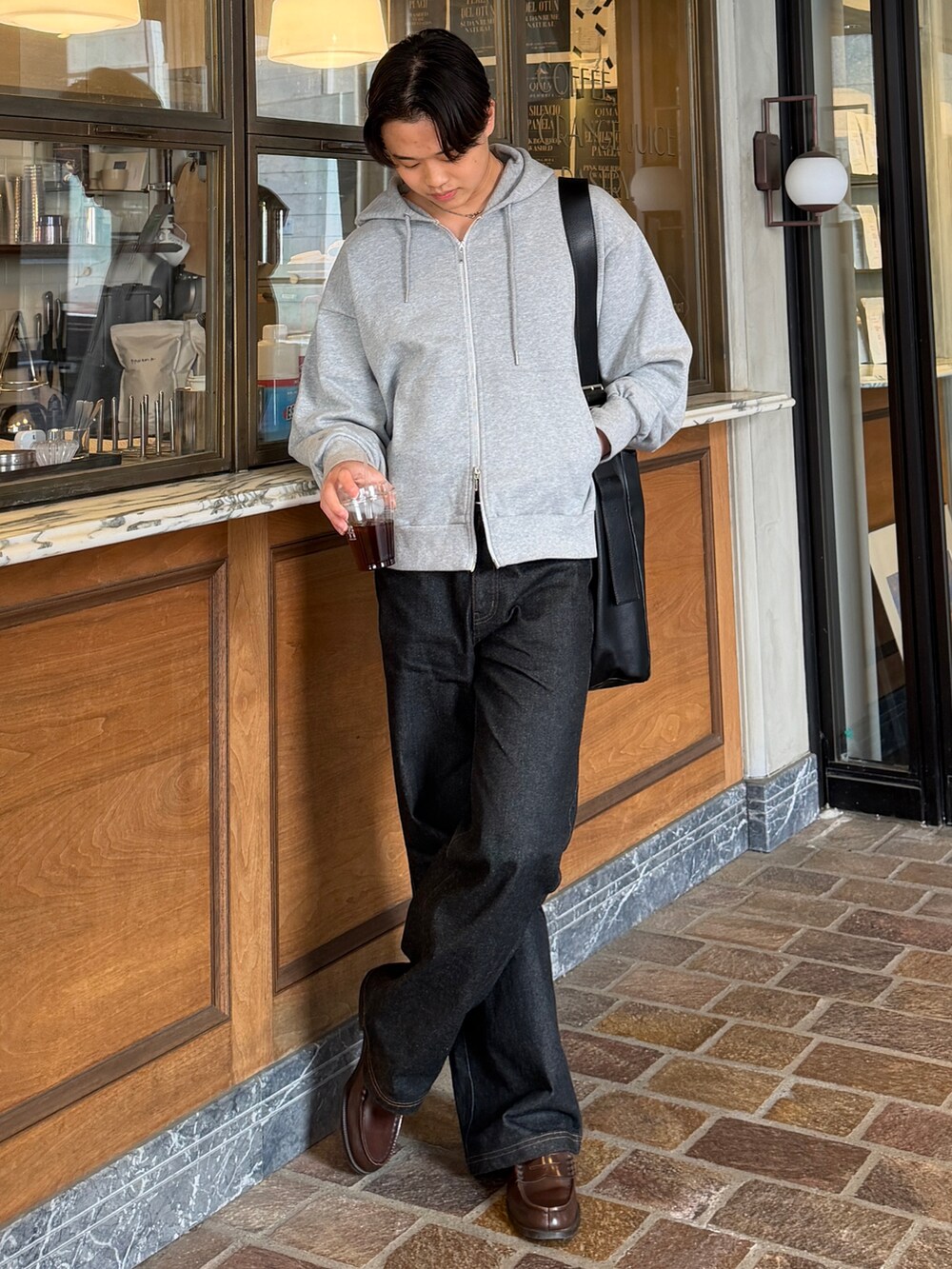 グレー系のパーカー、ブラック系のショルダーバッグ、ブラック系のデニムパンツを着用したメンズの春コーディネートの2枚目の写真