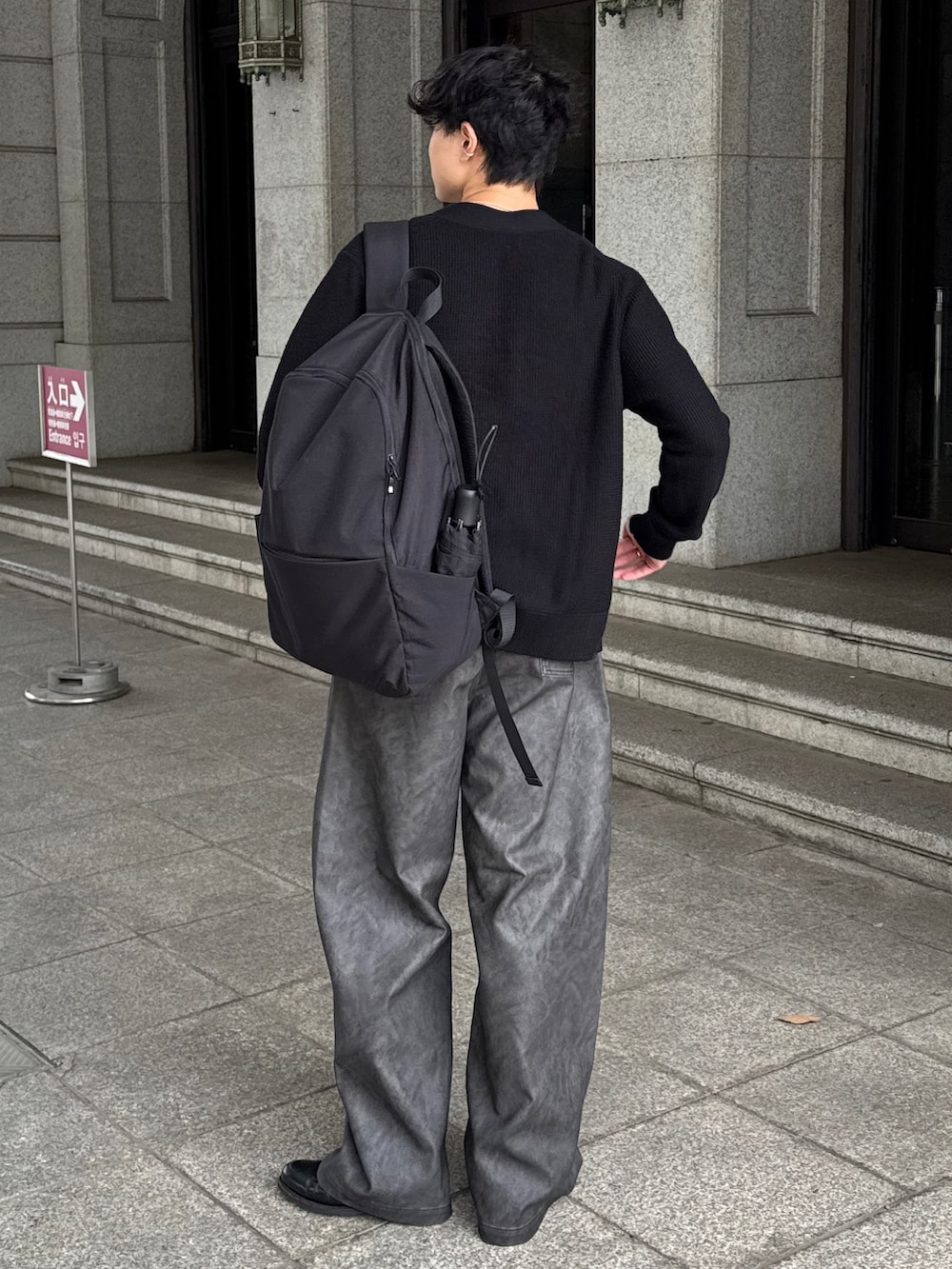 ブラック系のカーディガン/ボレロ、グレー系のパンツ、ブラック系のローファーを着用したメンズの秋コーディネートの4枚目の写真