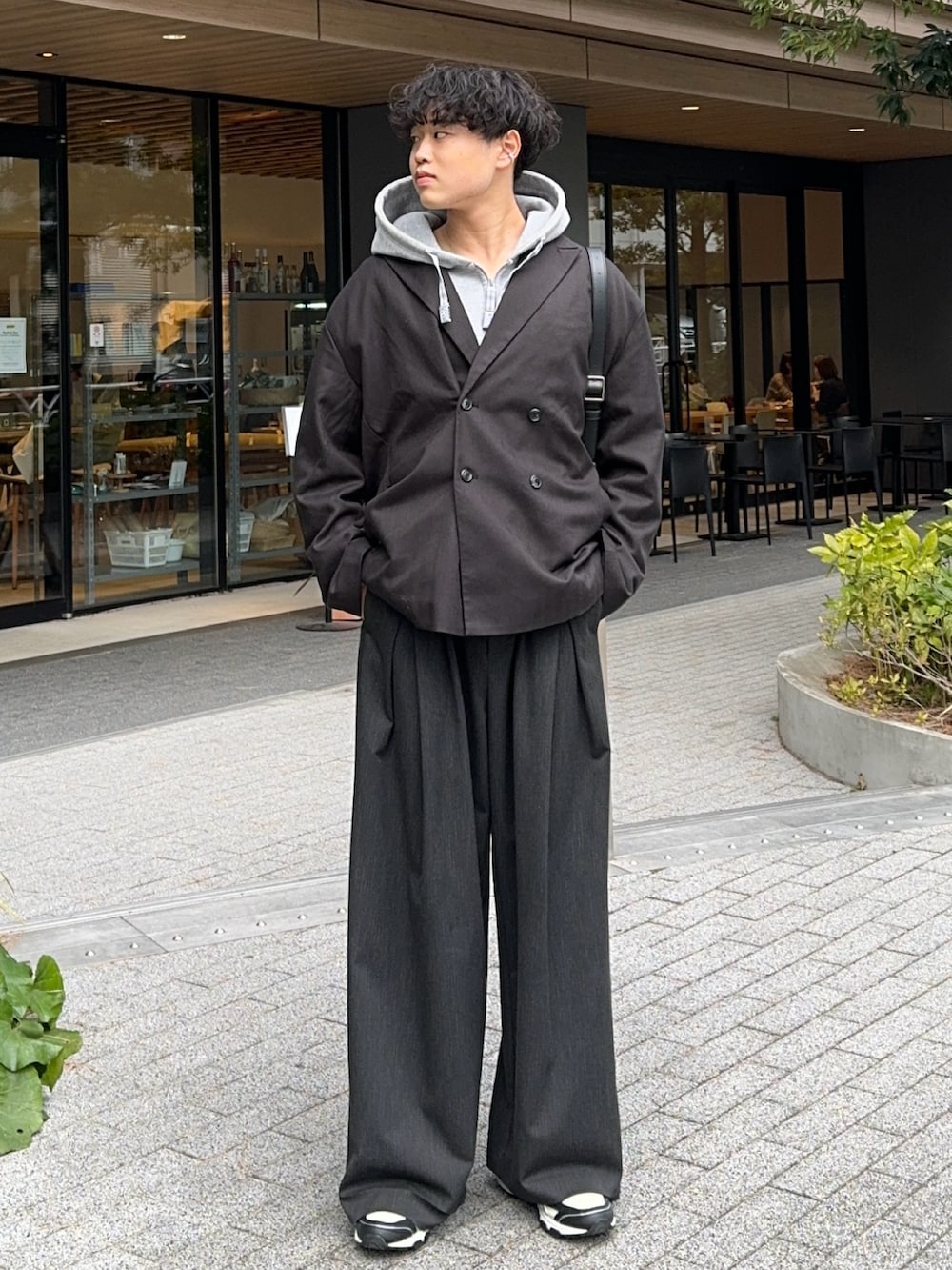 ブラック系のテーラードジャケット、グレー系のパーカー、ブラック系のスラックスを着用したメンズの冬コーディネートの2枚目の写真