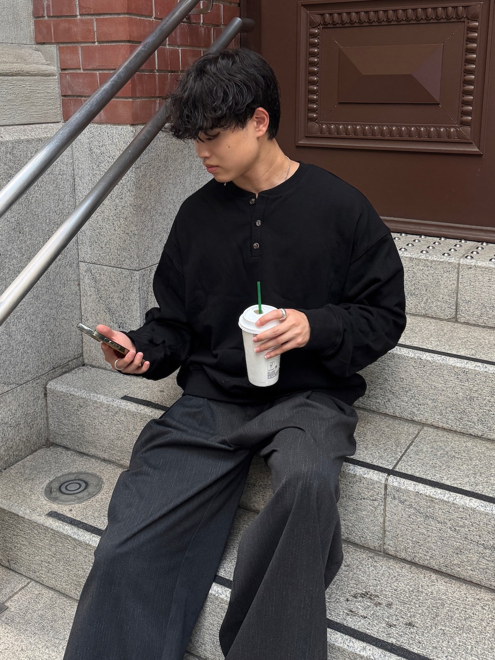 ブラック系のスウェット、グレー系のスラックス、シルバー系のブレスレットを着用したメンズの秋コーディネートの3枚目の写真