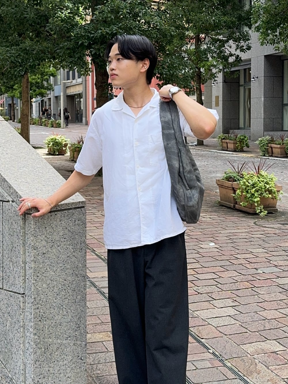 グレー系のショルダーバッグ、グレー系のスラックス、ブラック系のローファーを着用したメンズの夏コーディネートの4枚目の写真