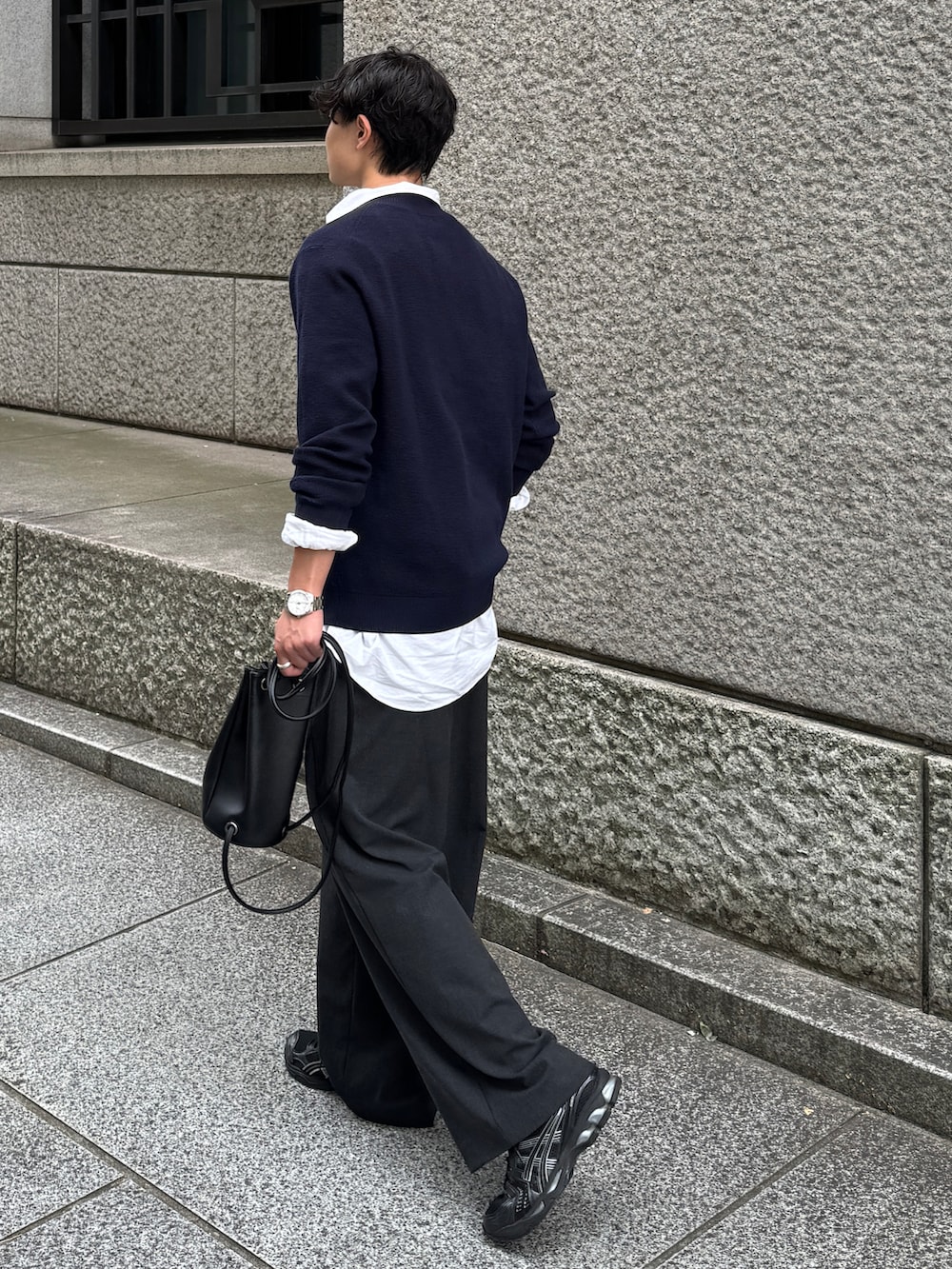 ブラック系のショルダーバッグ、グレー系のスラックス、ブラック系のスニーカーを着用したメンズの秋コーディネートの3枚目の写真