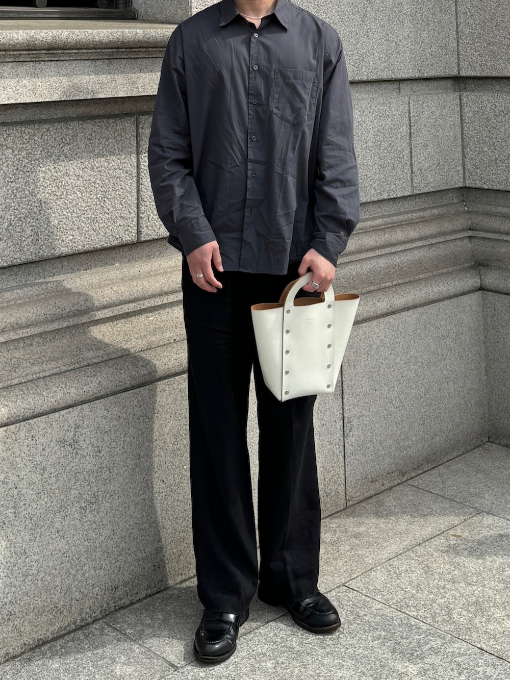ホワイト系のハンドバッグ、ブラック系のローファー、シルバー系のネックレスを着用したメンズの春コーディネートの3枚目の写真
