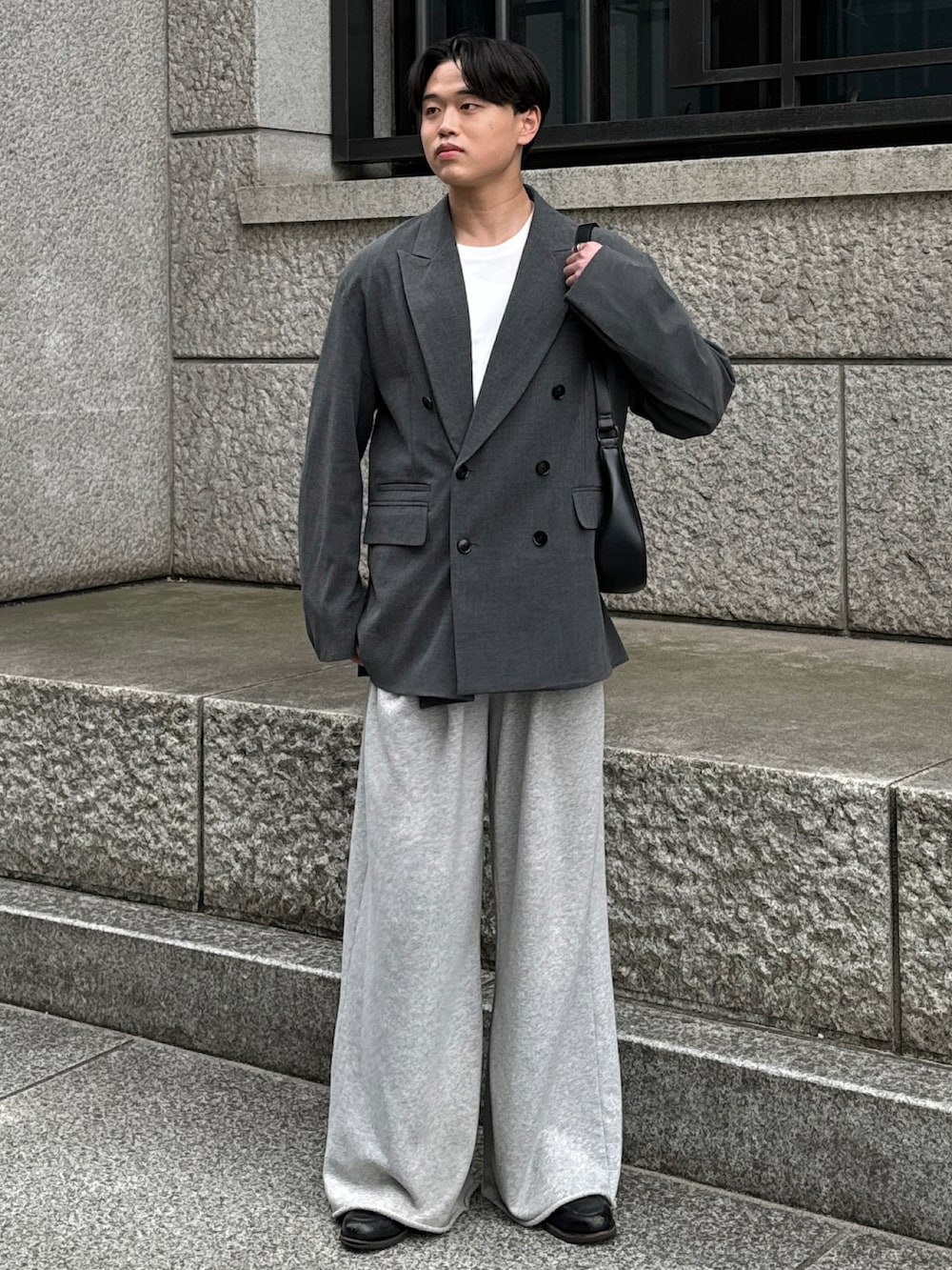 グレー系のテーラードジャケット、ブラック系のショルダーバッグ、グレー系のスウェットパンツを着用したメンズの春コーディネートの2枚目の写真