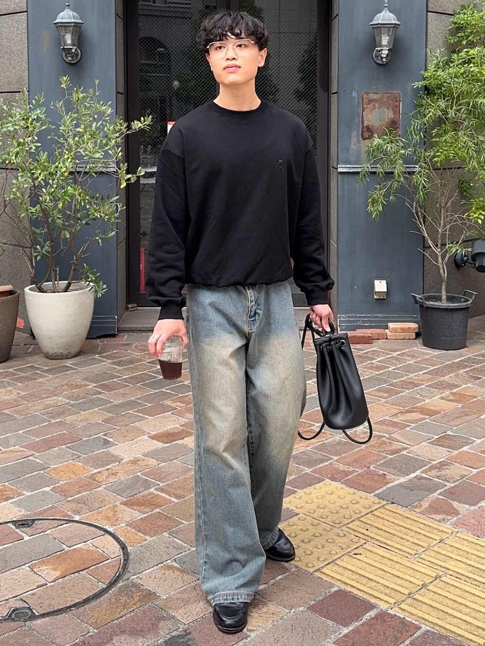 ブラック系のスウェット、ブルー系のデニムパンツ、ブラック系のショルダーバッグを着用したメンズの秋コーディネートの2枚目の写真