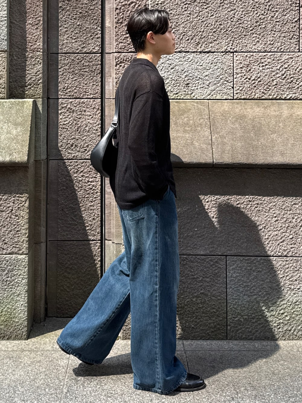 ブルー系のデニムパンツ、ブラック系のローファー、ブラック系のショルダーバッグを着用したメンズの秋コーディネートの3枚目の写真