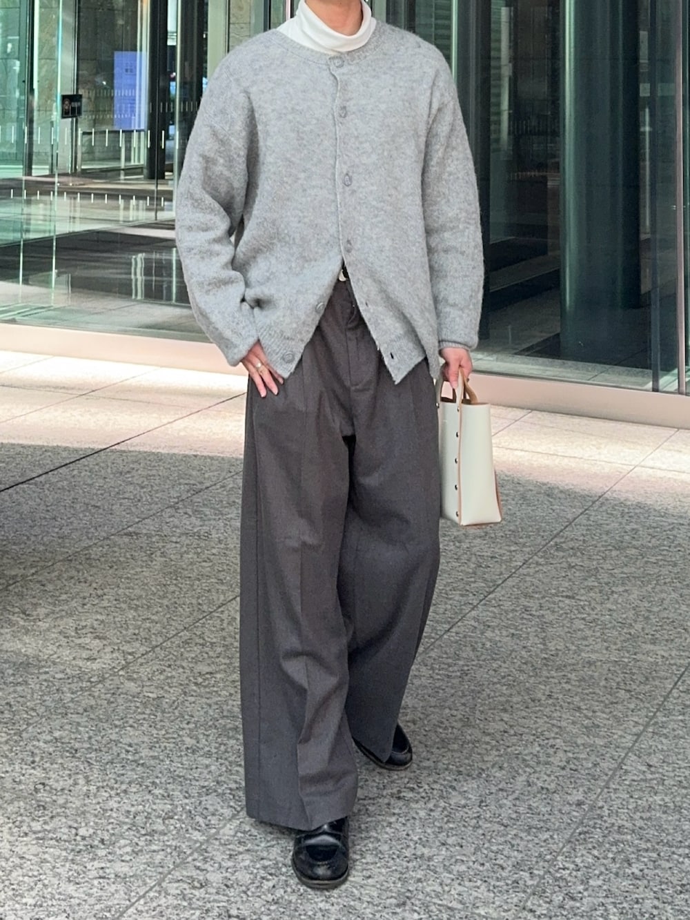 グレー系のカーディガン/ボレロ、ホワイト系のハンドバッグ、ブラック系のローファーを着用したメンズの冬コーディネートの3枚目の写真